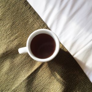 a warm cup of coffee resting on a bed in soft morning light