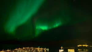 a green aurora bore over a city at night