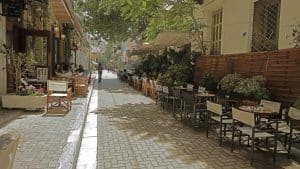 a street lined with tables and chairs next to trees