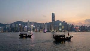 Hong Kong harbour at dusk with junks and city lights.