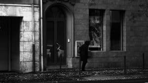 grayscale photo of man and woman walking on sidewalk