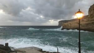 a street light sitting on the side of a cliff next to the ocean