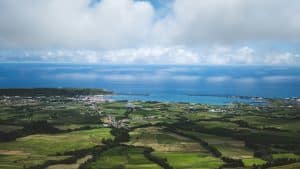 Rolling green hills meet the blue ocean under clouds.