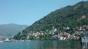 Buildings nestled on a tree-covered mountainside overlooking a lake.