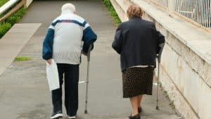 Elderly couple walking with crutches up stairs