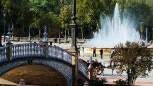 Bridge and fountain in a sunny park with people