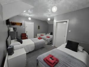 Bedroom at Manor Hotel Ballymoney with two beds and a red purse on the bed