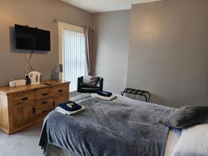 Double Room at Manor Hotel Ballymoney with a bed, chair and a television, County Antrim