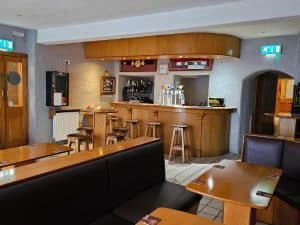 Bar in the restaurant with wooden tables and chairs at Manor Hotel Ballymoney