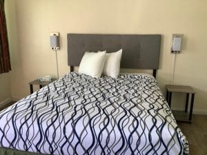 Queen Room at National 9 Motel in Santa Cruz with a single queen bed, tufted grey headboard, white pillows and patterned bedding