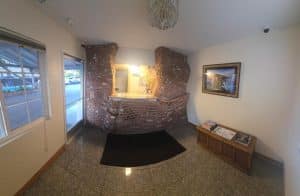 Lobby reception at National 9 Motel in Santa Cruz with a brick reception desk wall, glass-bead chandelier and tile floor