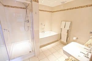 En-suite bathroom at The Grange Manor with a shower over bath, sink and chrome fittings, Grangemouth