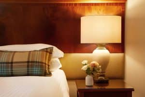 King Room at The Grange Manor with a king bed, lamp and flowers on a side table, Grangemouth
