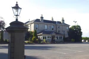 Sandstone Victorian facade of The Grange Manor with a street light at dusk, Grangemouth
