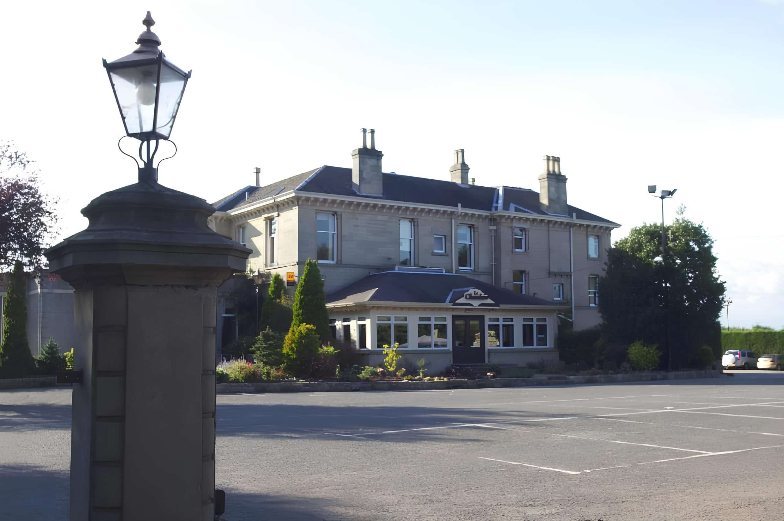 Sandstone Victorian facade of The Grange Manor at dusk with a street light in the foreground, Grangemouth