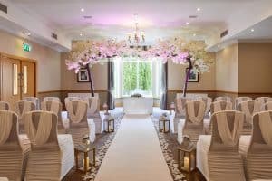 Wedding ceremony room at The Grange Manor with a row of chairs, a table and floral arrangements, Grangemouth