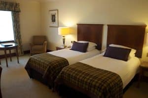 Twin Room at The Grange Manor with two beds and a chair, Grangemouth