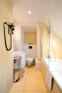 Private en-suite bathroom at Hotel Berkeley Paris with bath, shower over the bath and hairdryer