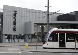 Edinburgh tram passing Haymarket station opposite Haymarket Station Rooms, Edinburgh