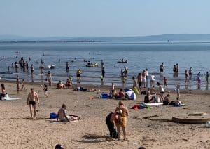 Families on the wide golden sand of Irvine Beach with the hills of Arran on the horizon, North Ayrshire