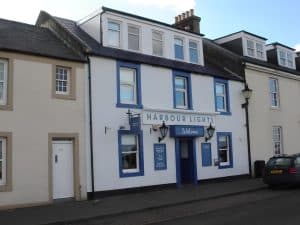 White and blue frontage of the Harbour Lights guest house and pub on Harbour Street, Irvine
