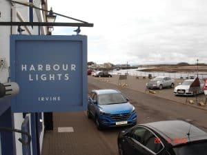 The harbourside quay at Irvine with parked cars and the curved Linthouse roof of the Scottish Maritime Museum beyond