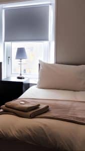 Single room at Harbourlights with a comfy bed, bedside lamp and a window over the harbour, Irvine
