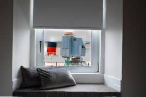 Window seat with cushions looking out over the harbour and a moored puffer boat in a Harbourlights twin room, Irvine