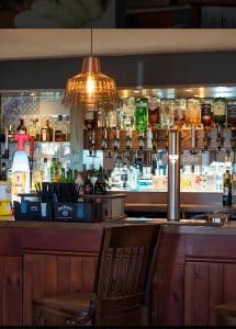 The Harbour Lights bar with stocked spirit shelves, a copper pendant light and a wooden counter, Irvine