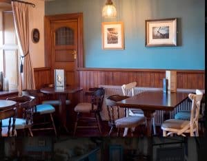 Blue-walled dining room at the Harbour Lights pub with wood panelling, framed nautical prints and set tables, Irvine