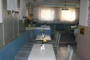 The breakfast room with blue banquette seating and white tables at Hostel Bad Goisern