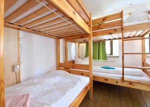 Pine bunk beds with white bedding in the six-bed dormitory at Hostel Bad Goisern