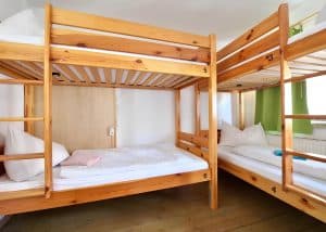 Single bed in a bright shared dormitory with pine bunks at Hostel Bad Goisern