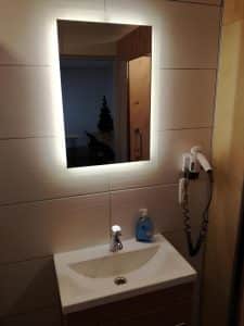 A modern shower room with a backlit mirror and timber vanity at Hostel Bad Goisern