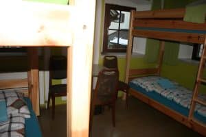 Four-bed dormitory with pine bunks, a table and a window at Hostel Bad Goisern