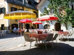 Sunny cafe terrace with parasols beside the yellow townhouse on the market square in Bad Goisern