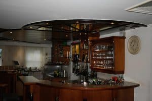 The downstairs bar counter with glassware and a wall clock at Hostel Bad Goisern