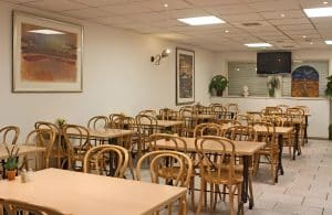 Light breakfast room with wooden bentwood chairs and a buffet counter at Hotel De Koopermoolen, Amsterdam