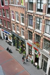 A cobbled Warmoesstraat streetscape in Amsterdam’s old town, steps from Hotel De Koopermoolen
