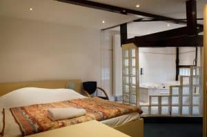 Double room at Hotel De Koopermoolen with a wooden headboard, wall lamps and blue curtains, Amsterdam