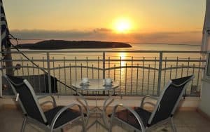 Sunrise over Mirabello Bay from a sea-view balcony at Pergola Hotel with two coffee cups on the table, Agios Nikolaos