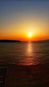 The sun rising on the horizon over a calm sea with golden reflections, seen from Pergola Hotel, Agios Nikolaos