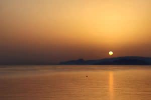 Golden sunrise over the sea seen from Pergola Hotel, the sun above the hills across Mirabello Bay, Agios Nikolaos