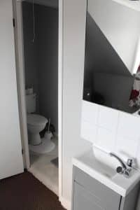 Compact en-suite bathroom with a white basin, tiled splashback and a toilet at The Vale Apart Hotel, Hull