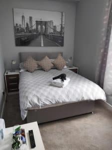 Double room at The Vale Apart Hotel with grey fan-pattern bedding and a black-and-white bridge print, Hull
