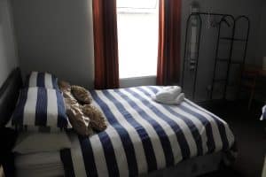 Standard double room at The Vale Apart Hotel with a blue-striped bed, red curtains and a clothes rail, Hull
