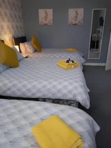 Family double room at The Vale Apart Hotel with grey fan-pattern bedding, gold cushions and rabbit prints, Hull