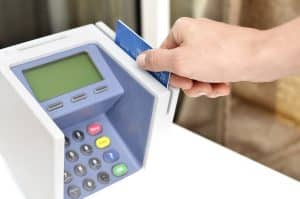 Hand passing a payment card through a card terminal, the moment a hotel pre-authorisation hold is placed