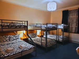 A Family Room at Helen's Hotel with a double bed and metal bunk beds, patterned bedding and folded towels