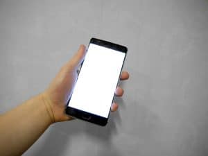 Hand holding a smartphone with a blank screen, the moment a hotel payment message arrives